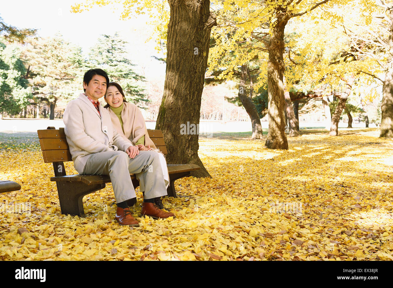 La haute couple japonais assis sur un banc dans un parc de la ville Banque D'Images
