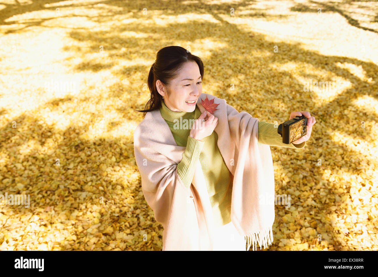 Japonais Senior woman taking a dans un parc de la ville selfies en automne Banque D'Images