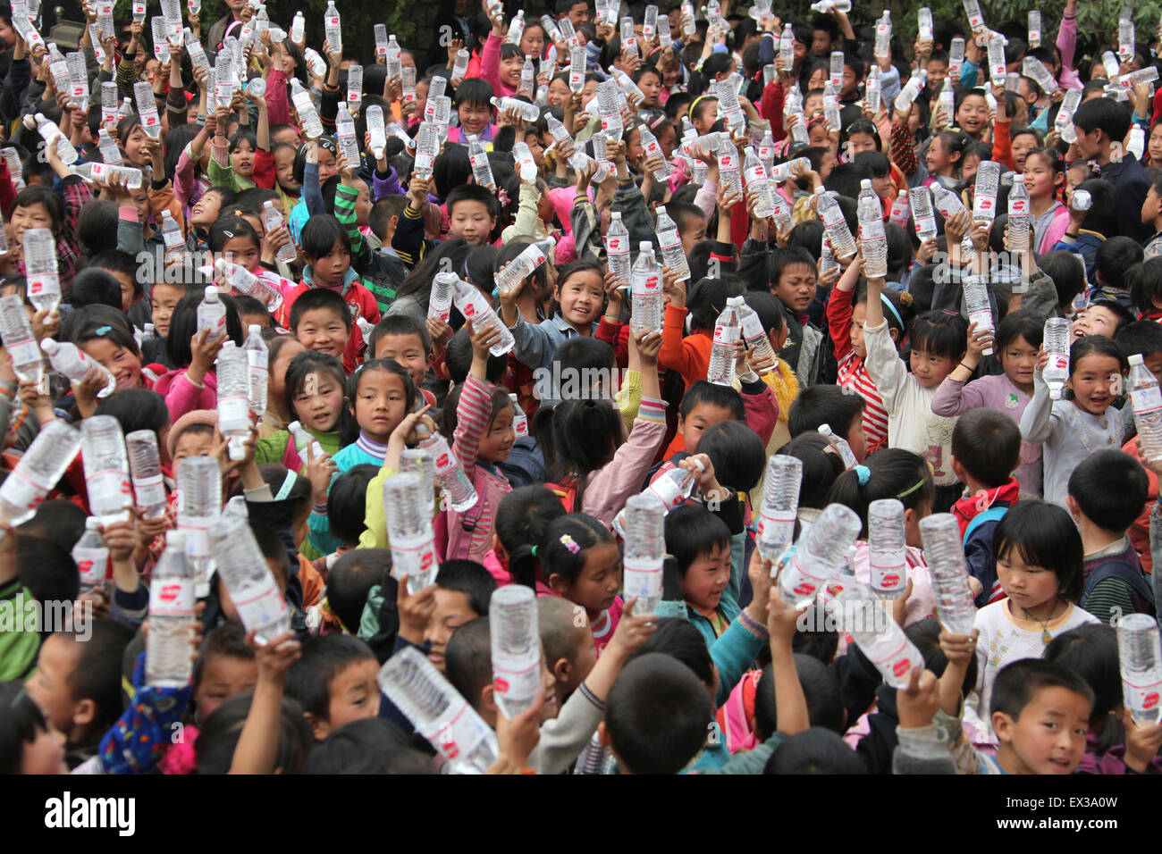 Les élèves de l'école élémentaire Tianwan espère afficher leur eau en bouteille getten donné par une société à l'école primaire de l'drou Banque D'Images