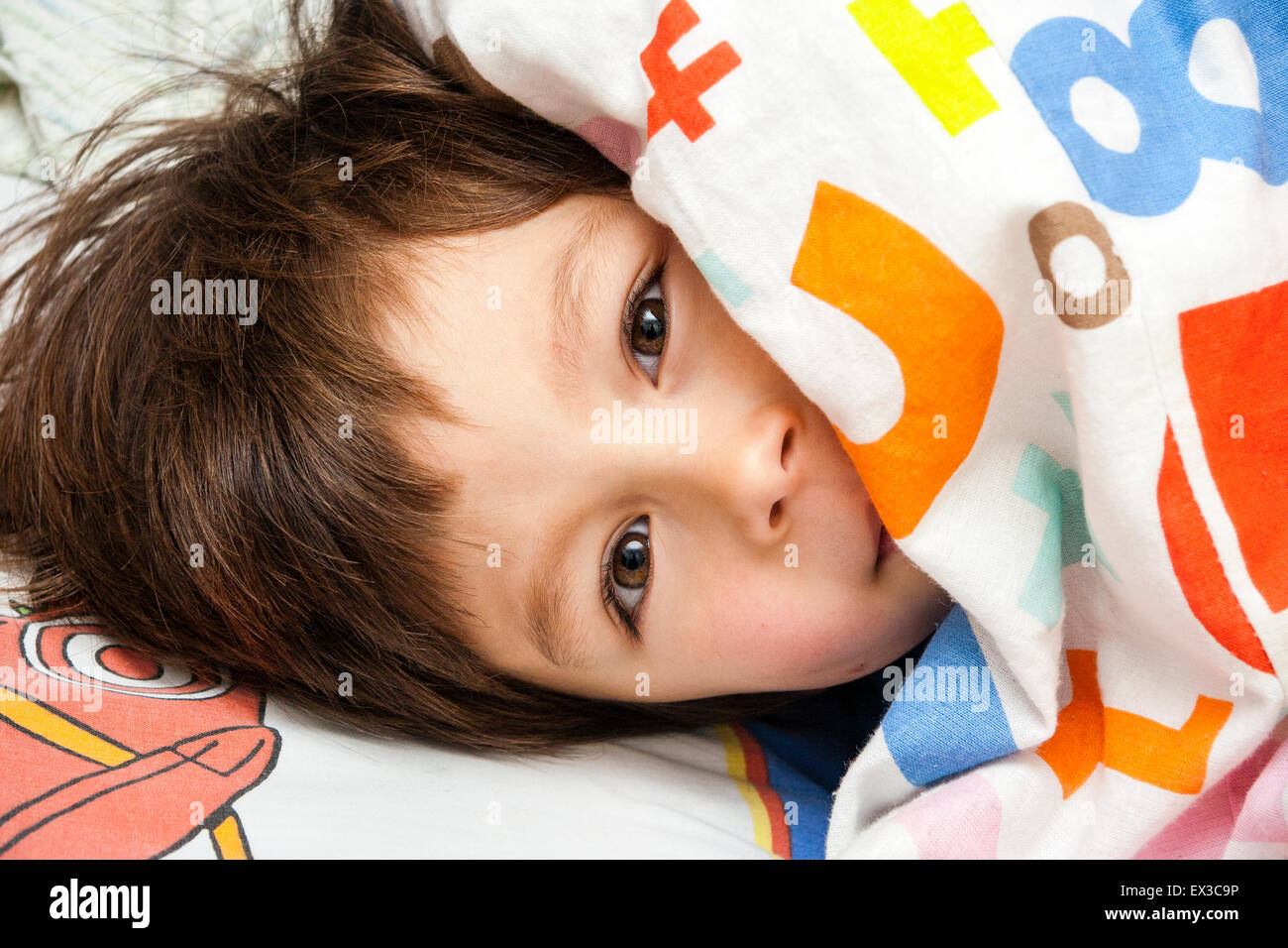 Bebe Garcon 3 4 Ans Les Cheveux Bruns Blottie Dans Le Lit Avec Couette Couvrant Partiellement Visage Alors Qu Il Jette Dehors Eye Contact Avec Viewer Photo Stock Alamy
