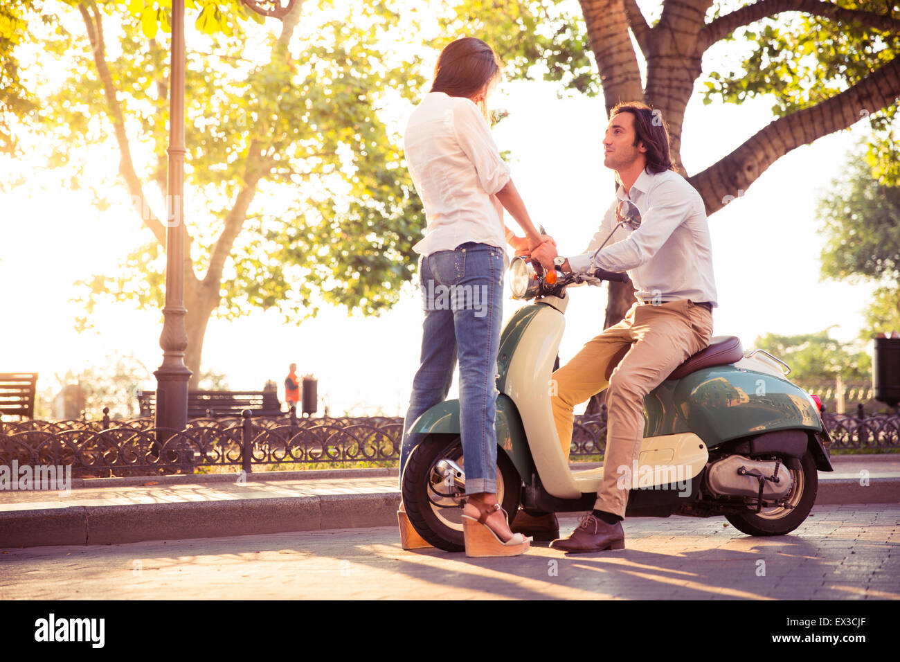 Jeune couple romantique glissant sur un scooter à l'extérieur Banque D'Images