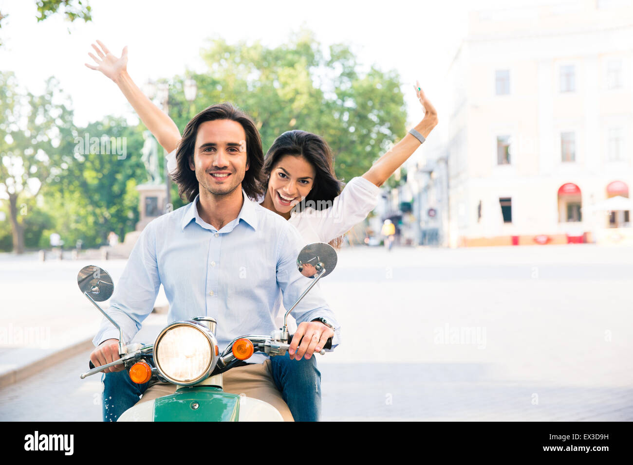 Cheerful couple à cheval sur un scooter en ville Banque D'Images