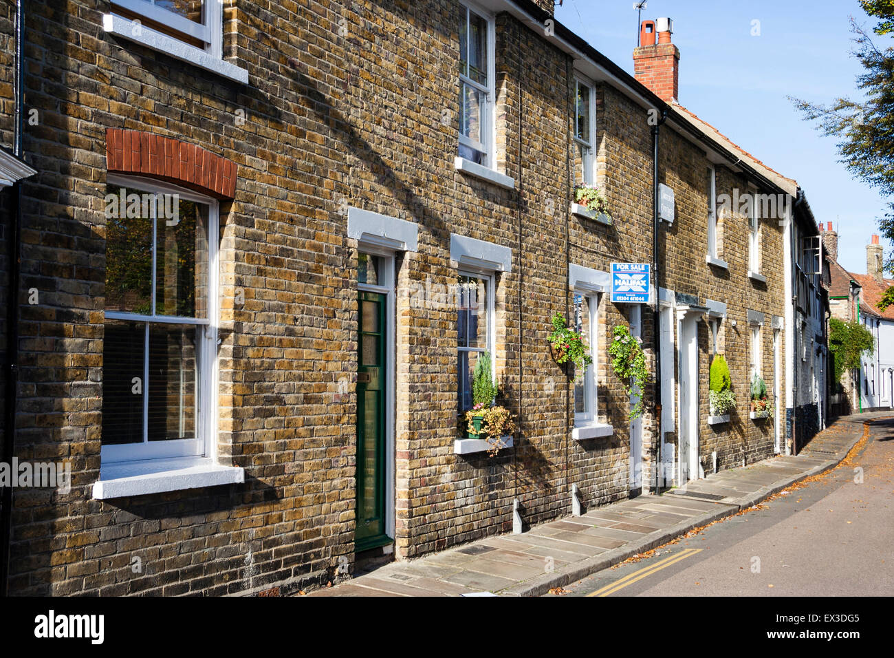 Terrasse rangée de maisons du 19e siècle sans façade jardins le long de la rue étroite de la vieille ville de Sandwich en Angleterre. L'on a 'à vendre'. Banque D'Images