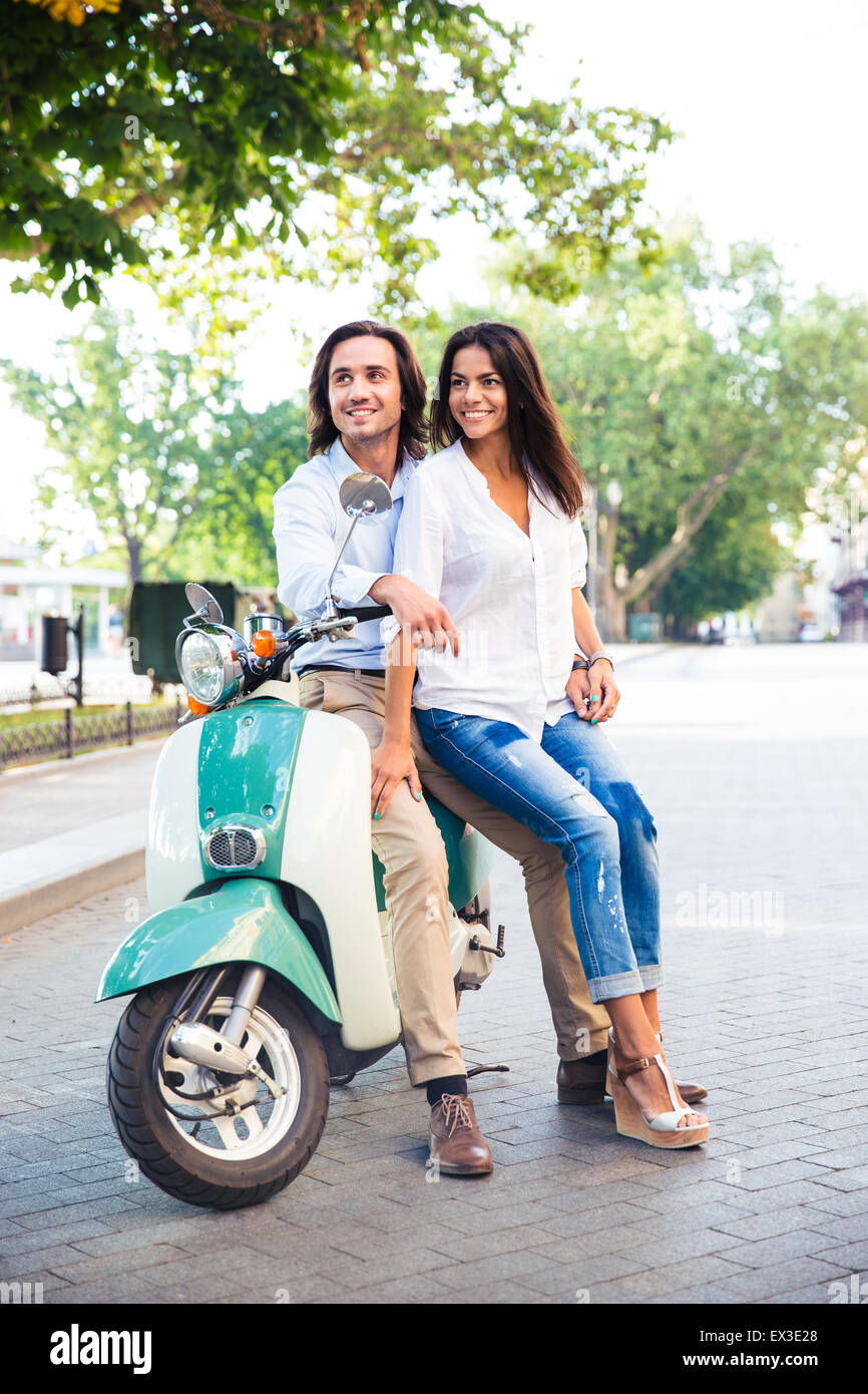 Happy young couple en scooter à la route à l'extérieur Banque D'Images
