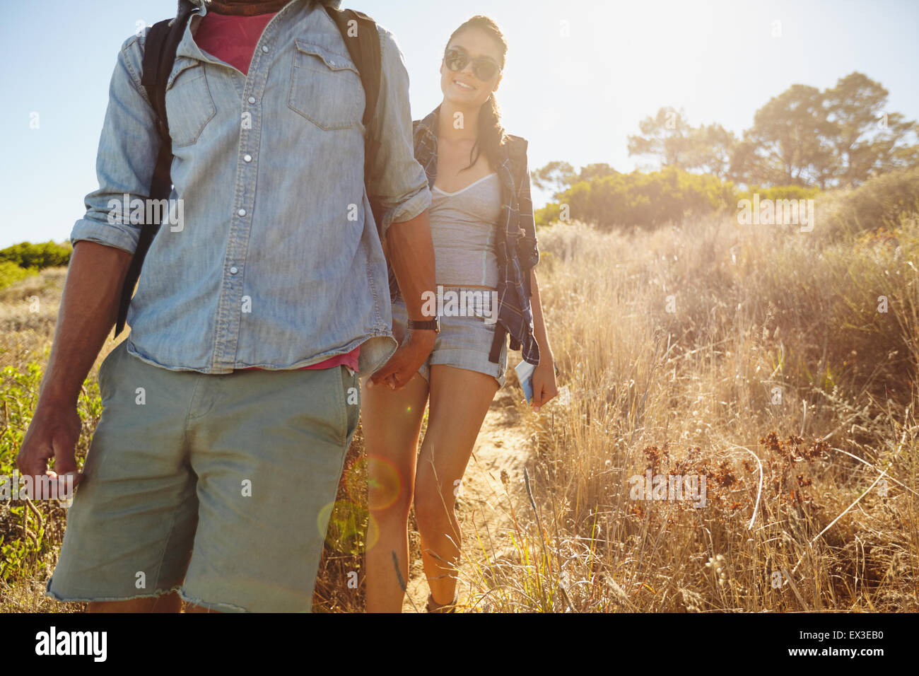 Image de jeune femme en randonnée dans les montagnes avec son petit ami en face. Couple en train de marcher en descente sur des vacances d'été. Banque D'Images