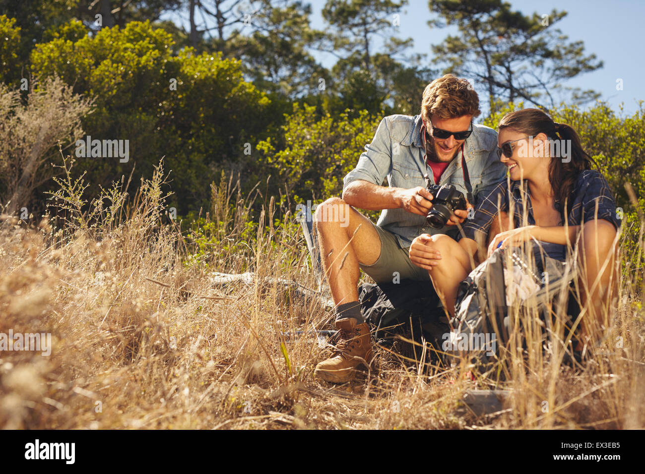 Young couple outdoors regarder des photos sur l'appareil-photo. Portrait homme et femme sur la randonnée en faisant une pause. Banque D'Images