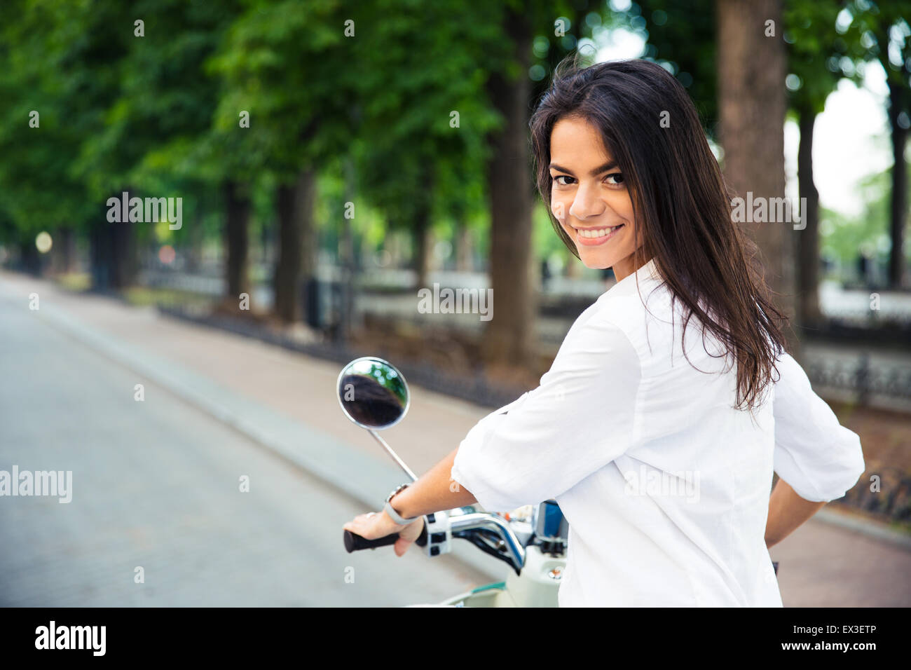 Happy woman riding sur un scooter et looking at camera Banque D'Images