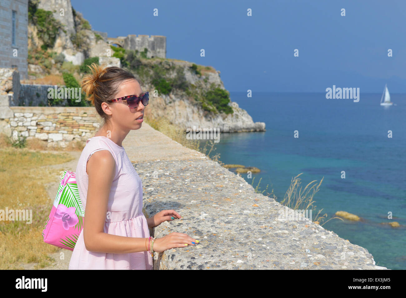 À la fille à la mer de la nouvelle forteresse de kerkyra portant robe rose et lunettes Banque D'Images