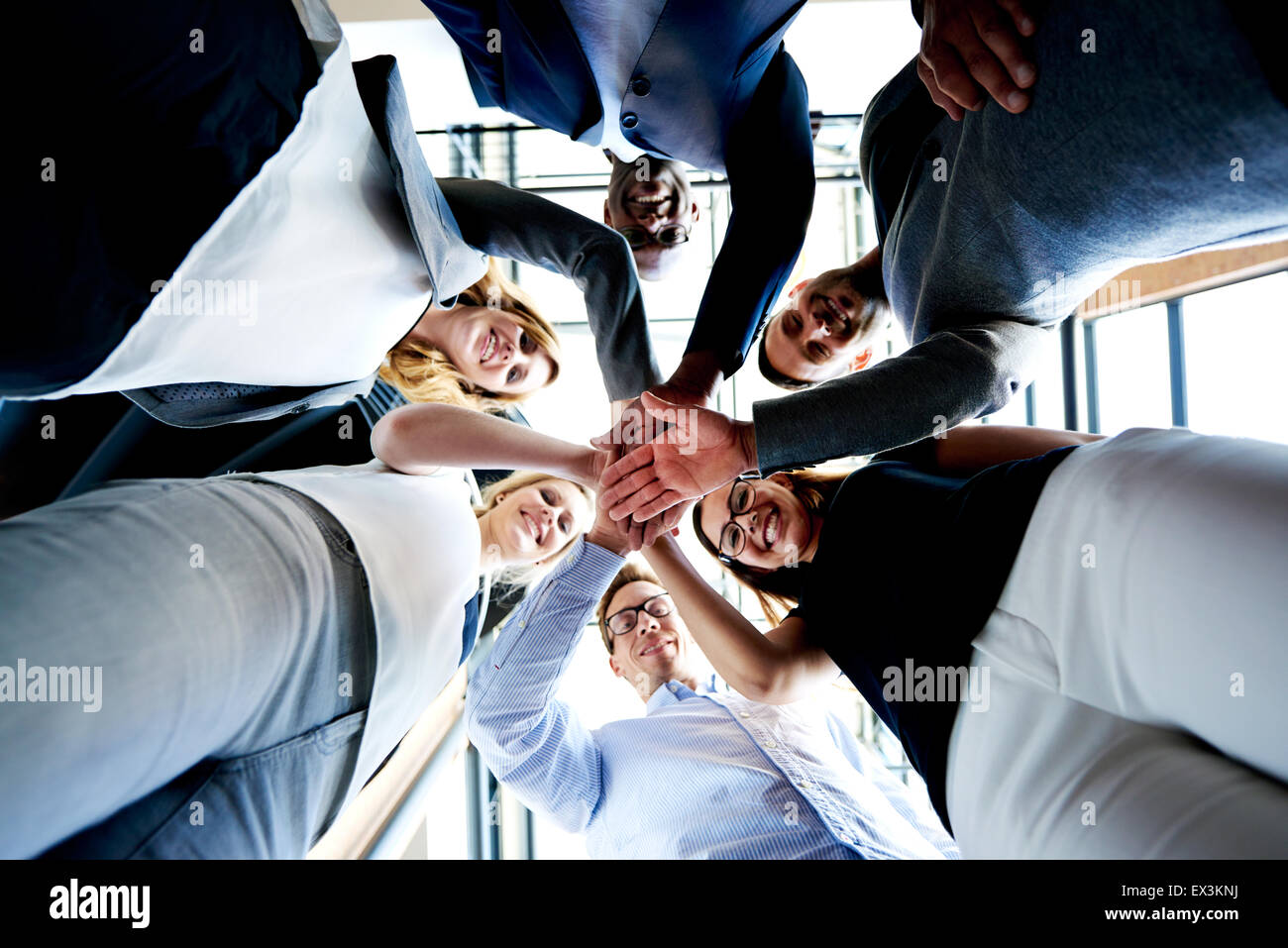 Groupe de jeunes cadres debout dans un cercle avec les mains à la recherche vers le bas. Banque D'Images