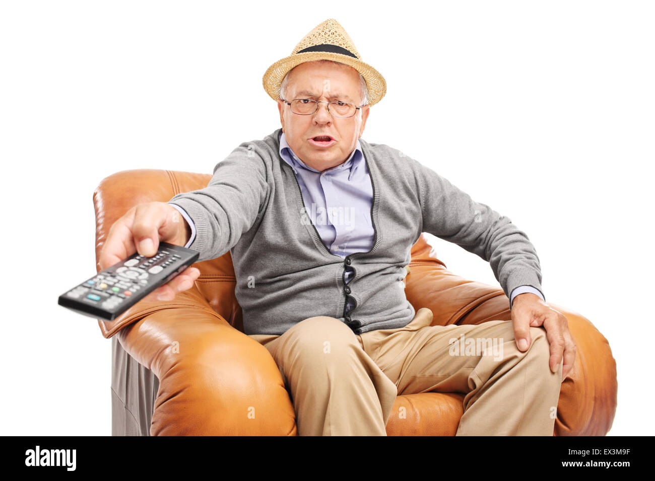 Angry man en appuyant sur les boutons d'une télécommande assis dans un fauteuil isolé sur fond blanc Banque D'Images