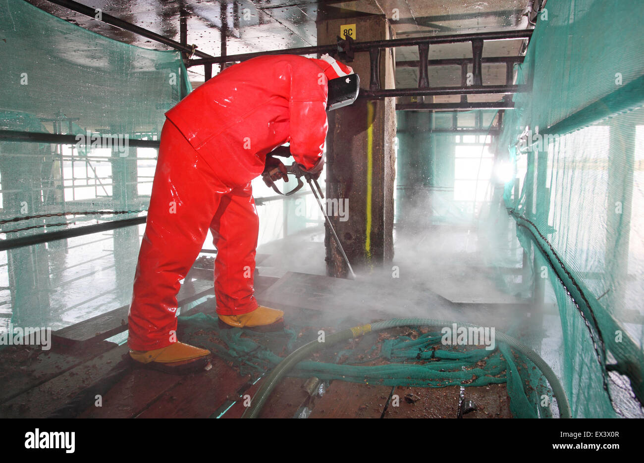 Un entrepreneur utilise un jet d'eau haute pression pour retirer le béton lors de la réparation de la structure de support de la rampe de chargement du véhicule de ferry de Woolwich. Londres, Royaume-Uni. Banque D'Images