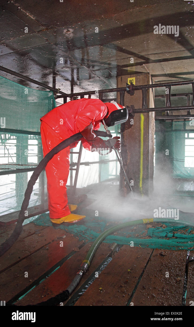 Un entrepreneur utilise un jet d'eau haute pression pour retirer le béton lors de la réparation de la structure de support de la rampe de chargement du véhicule de ferry de Woolwich. Londres, Royaume-Uni. Banque D'Images