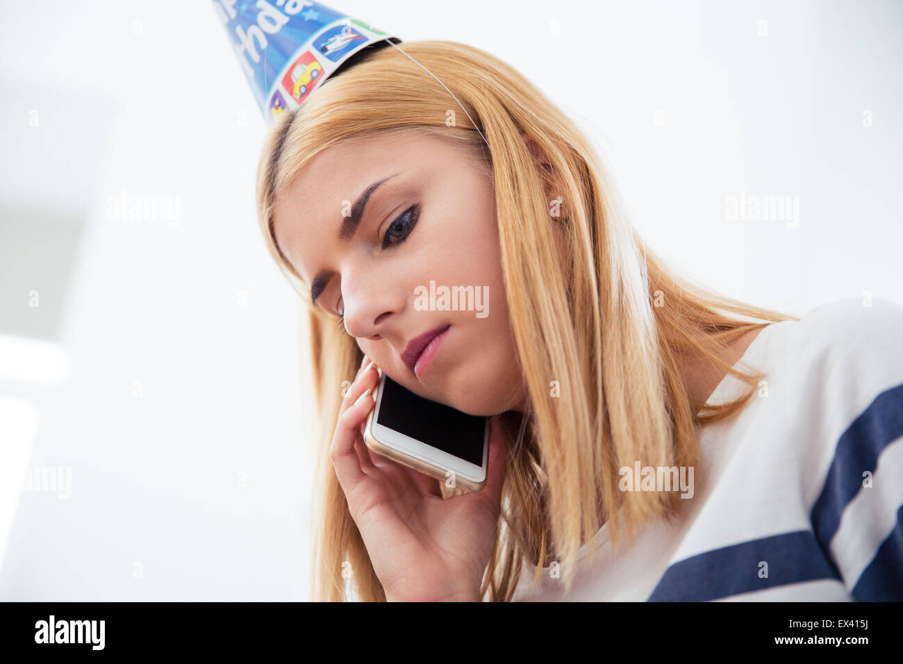 Jeune femme blonde avec party hat parler au téléphone Banque D'Images