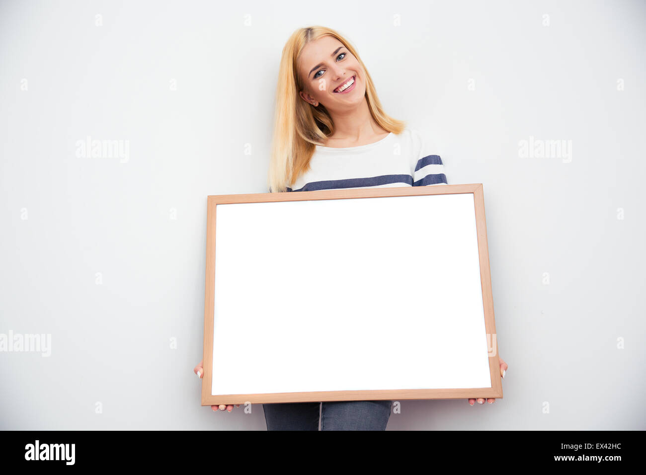 Young casual businesswoman holding blank board sur fond gris Banque D'Images