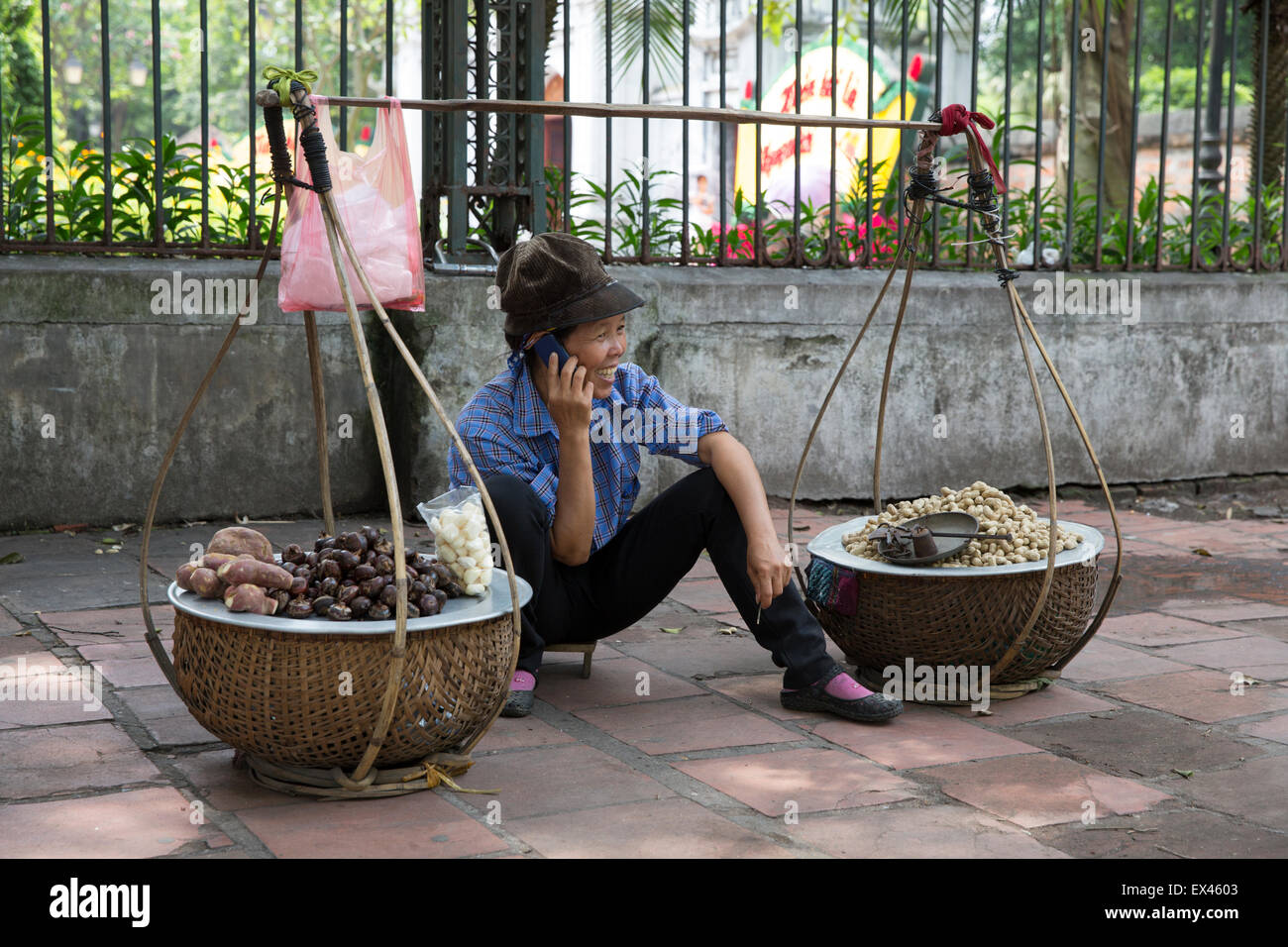 Hanoi Vietnam femme vend des marrons tout en parlant sur son téléphone portable à l'extérieur du Temple de la littérature Banque D'Images