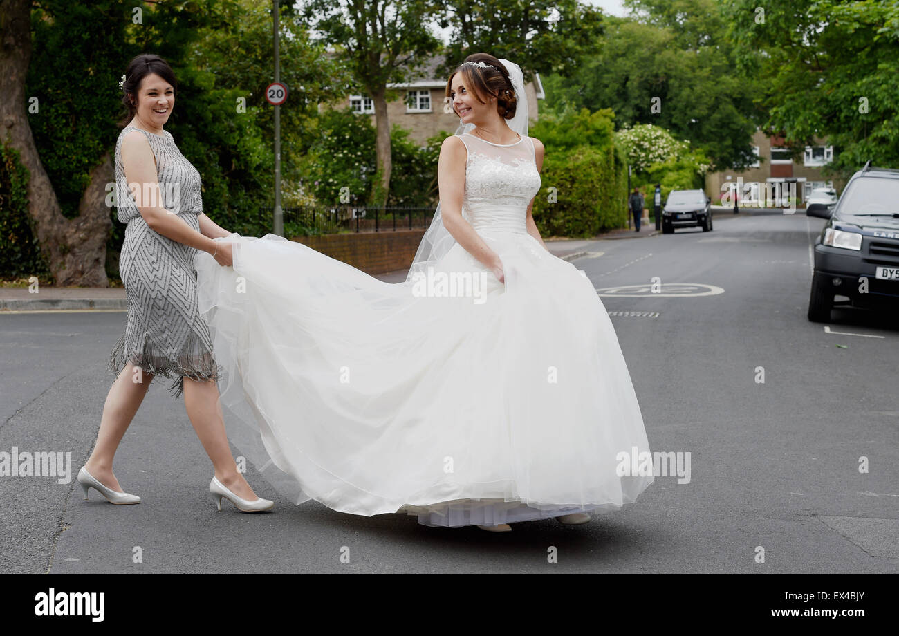 Belle jeune femme mariée en robe blanche le jour de son mariage l'aide de  l'autre côté de la rue par son témoin Photo Stock - Alamy