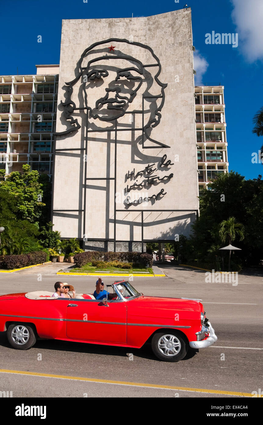 Vue verticale de touristes conduite par le Che Guevara murale dans une vieille voiture vintage à La Havane, Cuba. Banque D'Images