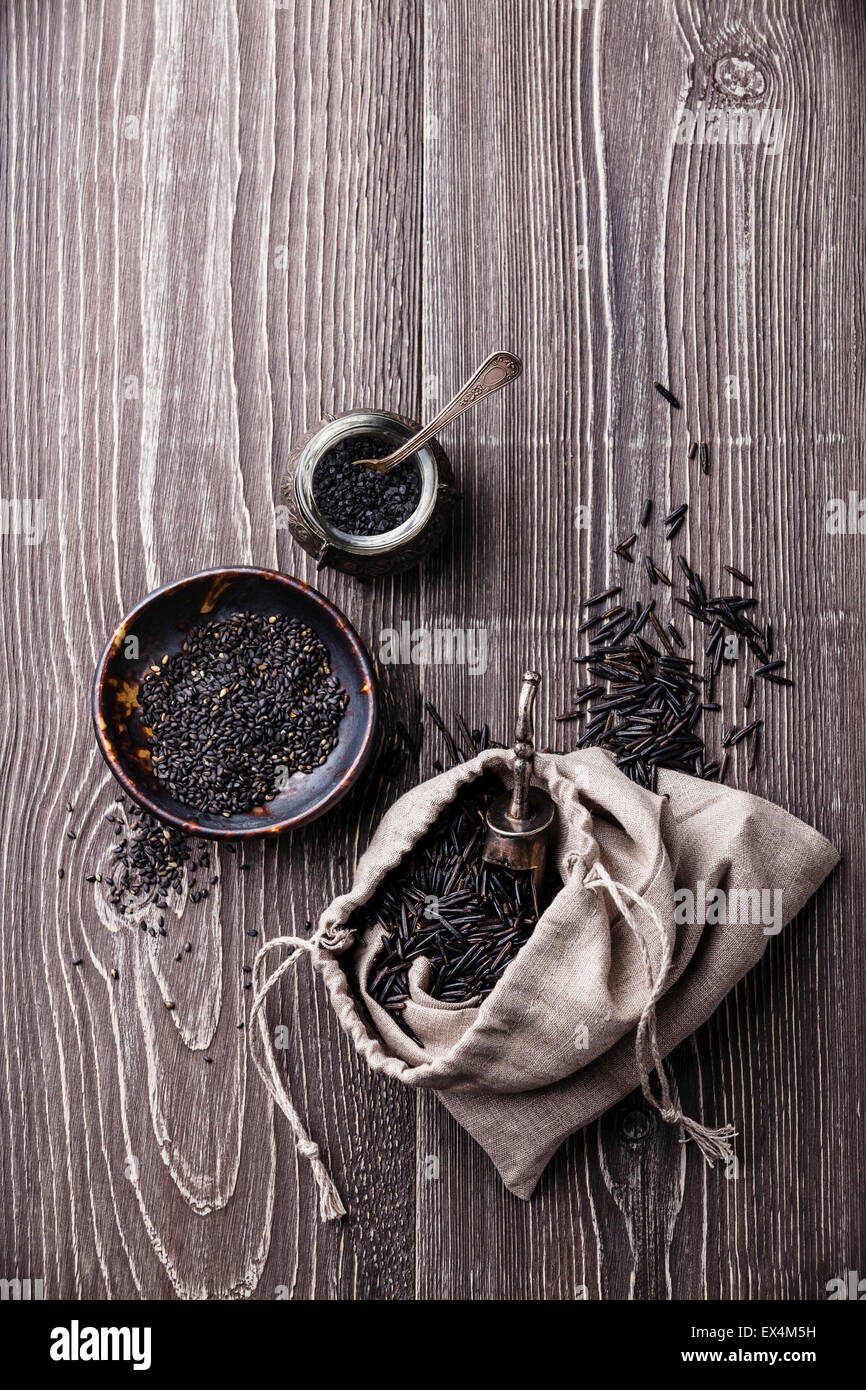 Matières noir Ingrédients alimentaires - riz sauvage, graines de sésame, sel noir sur fond de bois gris Banque D'Images