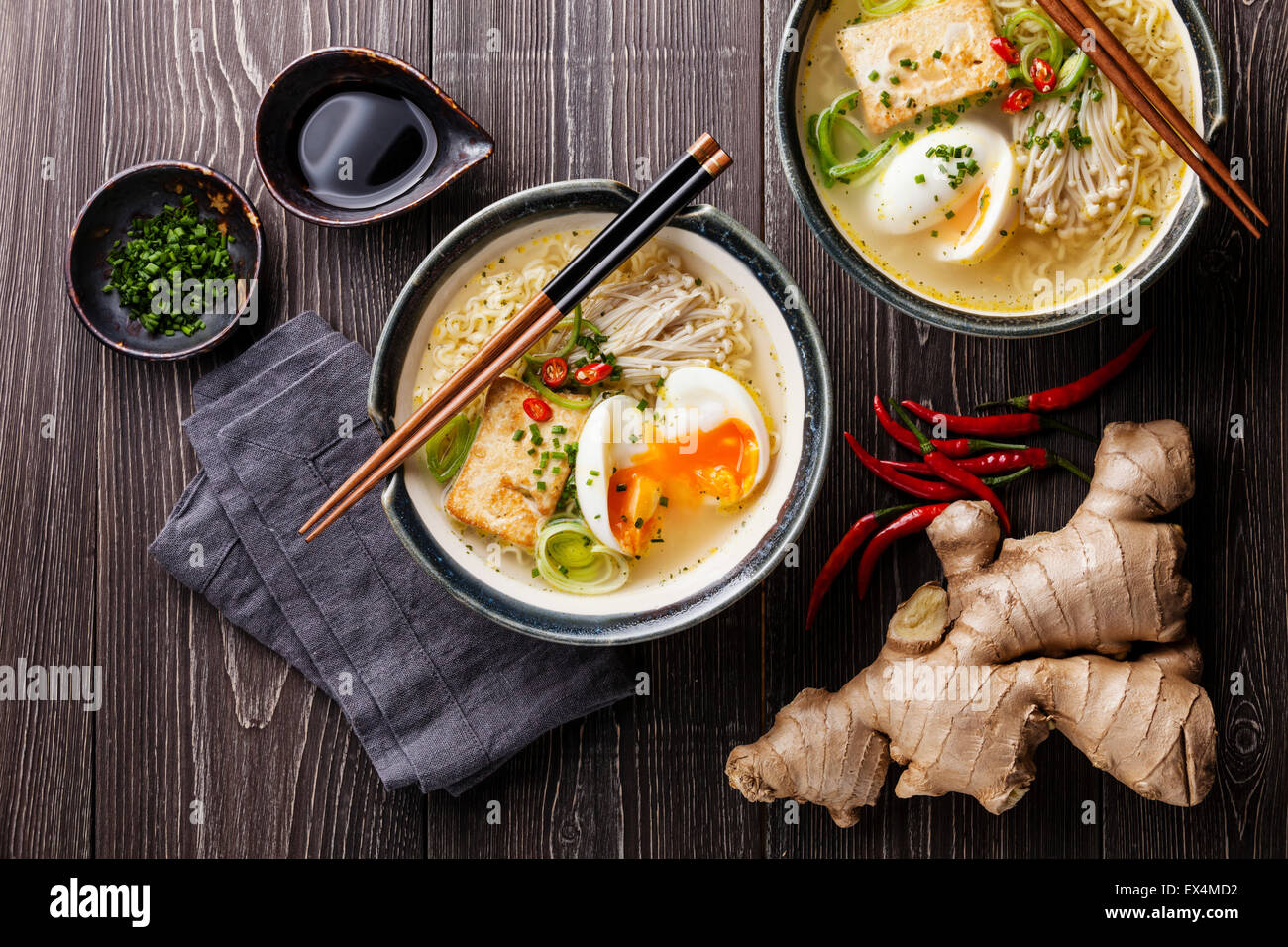 Nouilles ramen Miso asiatique avec des œufs, tofu et enokis dans des bols sur fond de bois gris Banque D'Images