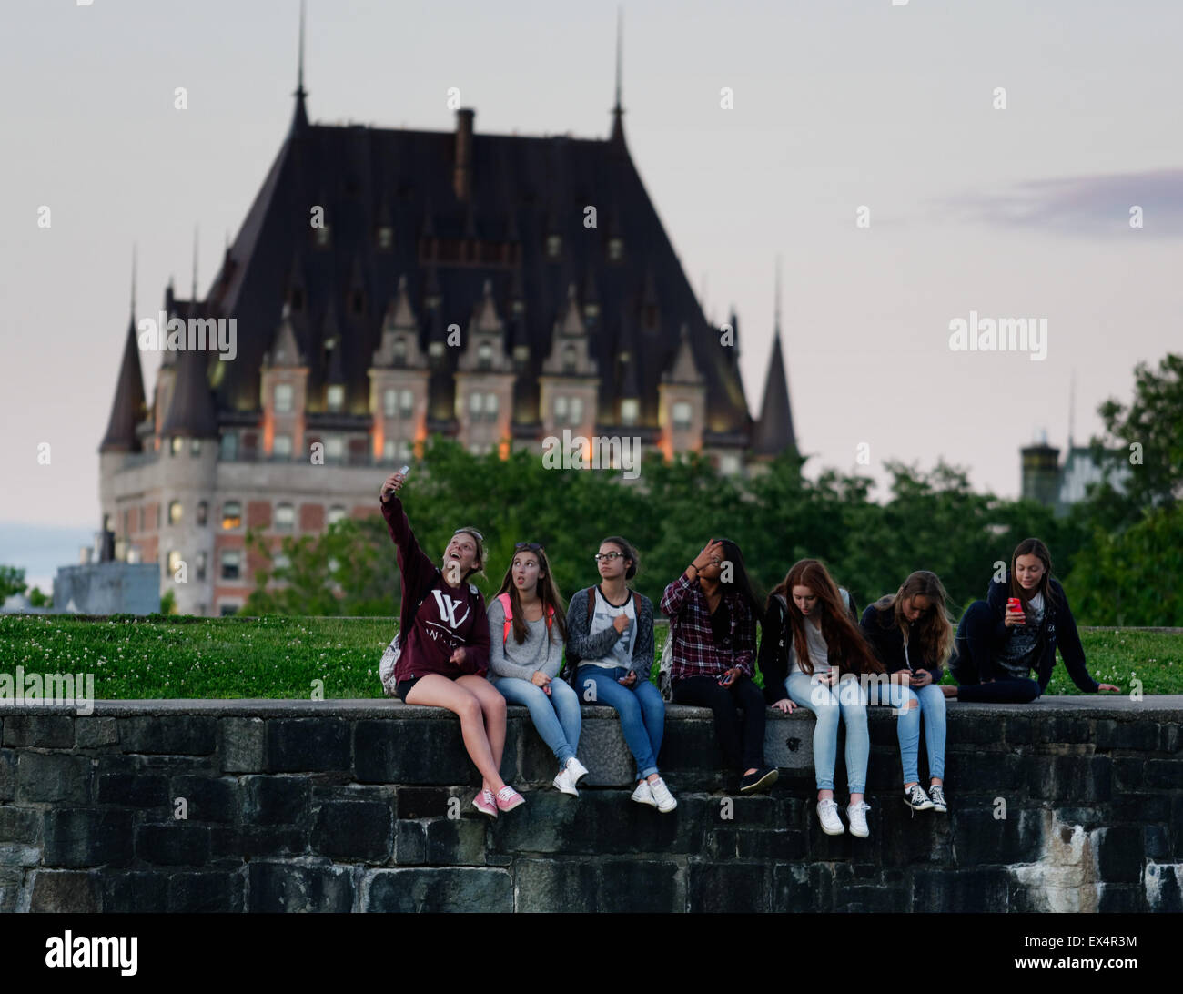 Un groupe de jeunes filles s'assit en prenant vos autoportraits en face du Château Frontenac à Québec Banque D'Images