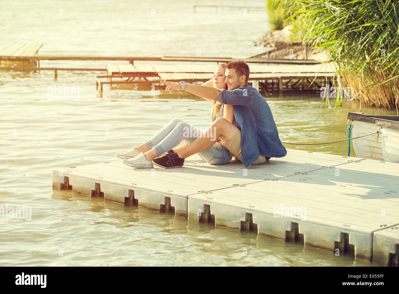 Couple amoureux assis sur la jetée, embrace Banque D'Images