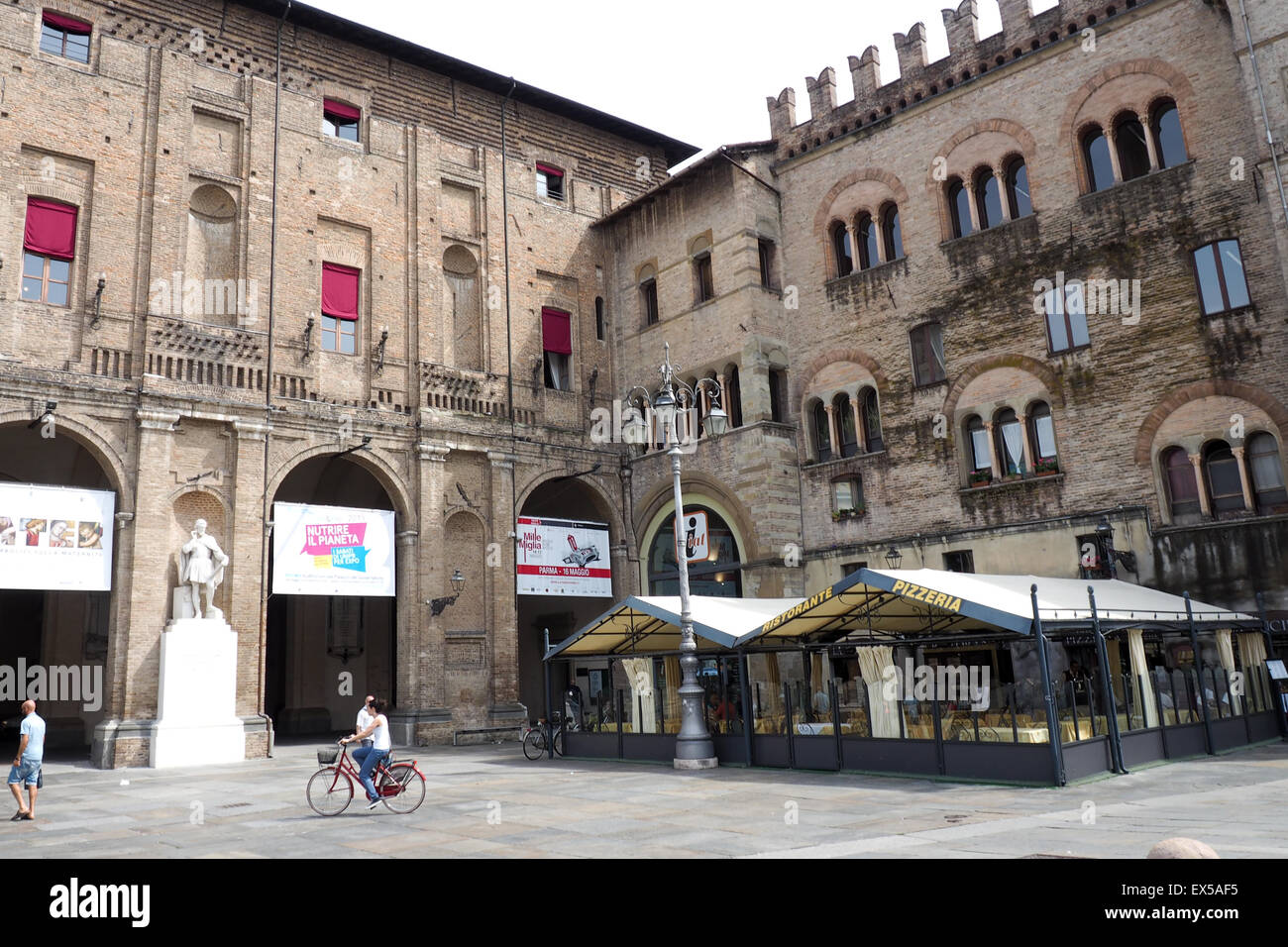 Un homme, et une femme cycliste traversant Piazza Giuseppe Garibaldi, Parme. Banque D'Images