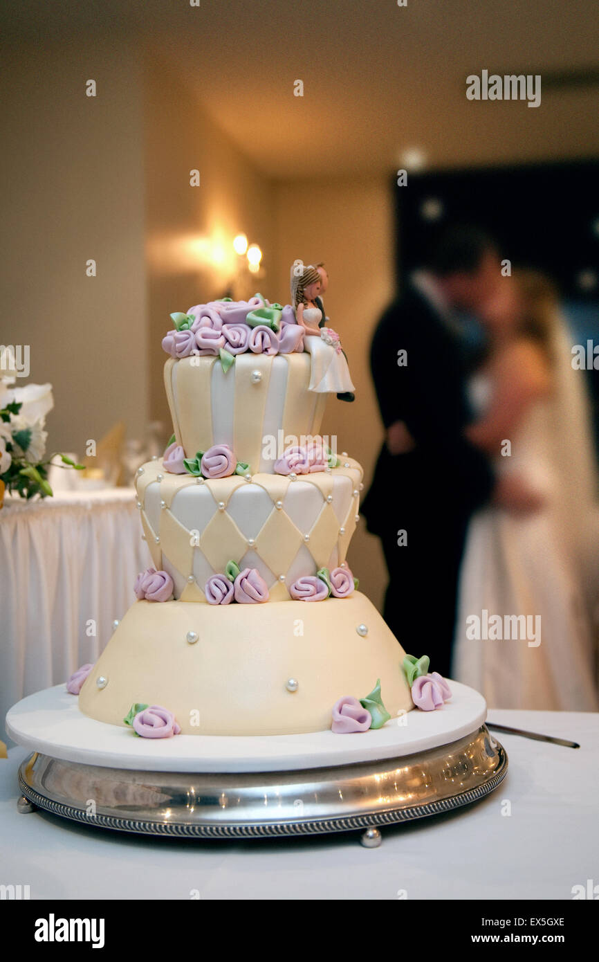 Gâteau de mariage décoré avec Bride and Groom kissing in the background Banque D'Images