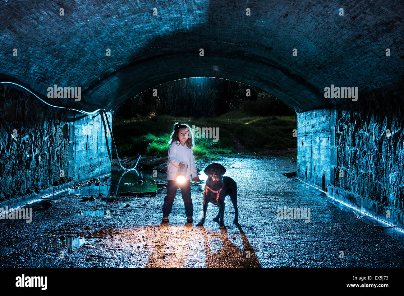 Petite fille et son chien dans un tunnel sombre. Banque D'Images