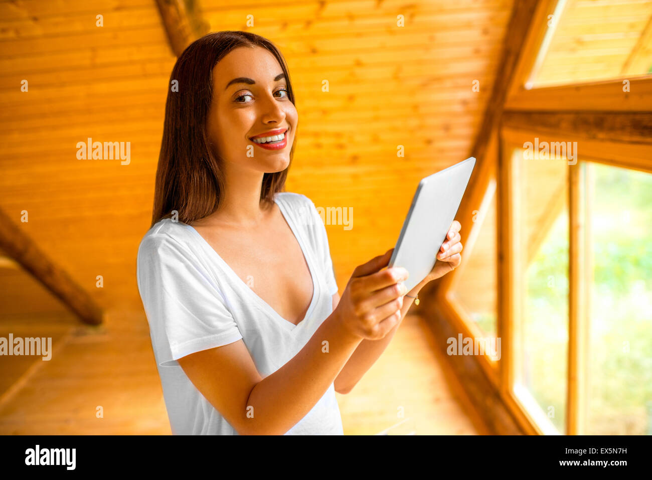 Femme avec le comprimé dans la maison en bois Banque D'Images