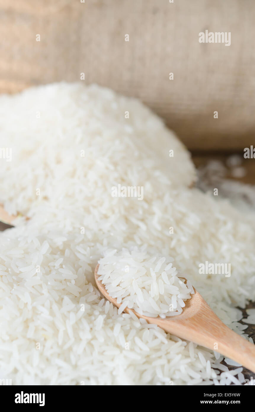 Les grains de riz blanc avec une cuillère de bois sur table en bois Banque D'Images