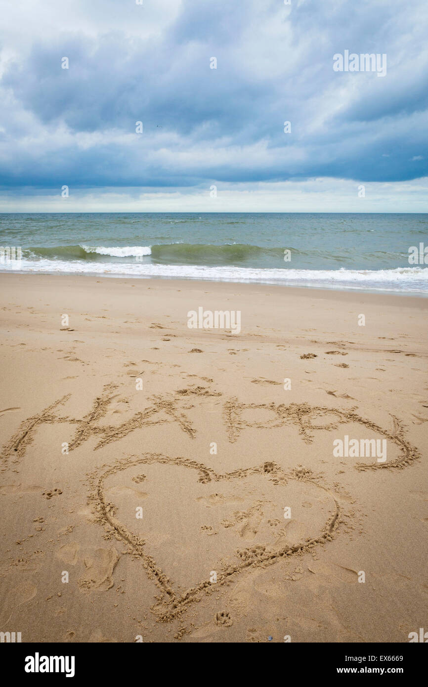 L'Europe, Pays-Bas, Zeeland, un coeur et le mot heureux dans le sable à la plage entre Oostkapelle Vrouwenpolder et sur la p Banque D'Images