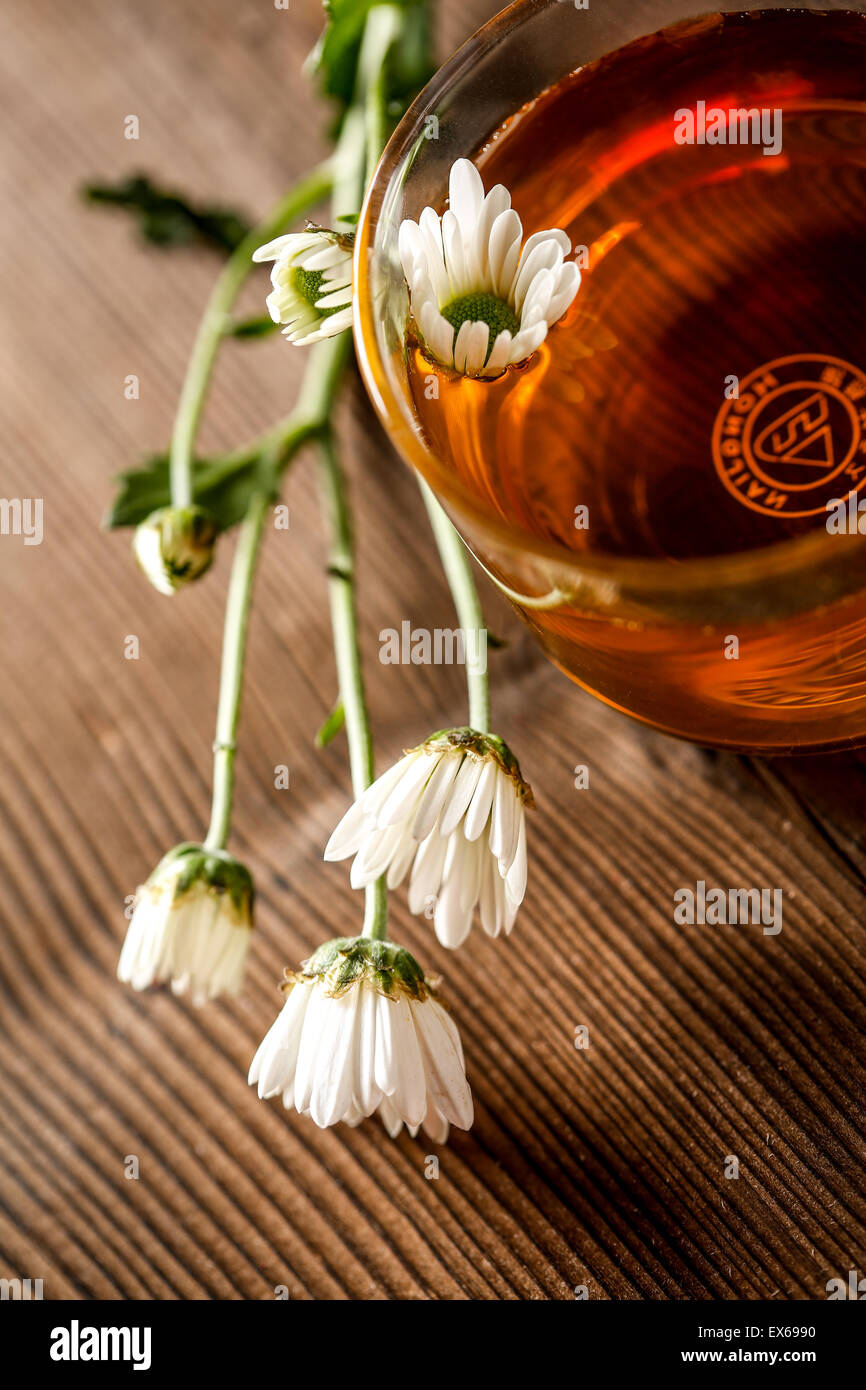 Tisane dans une tasse en verre et fleurs Banque D'Images