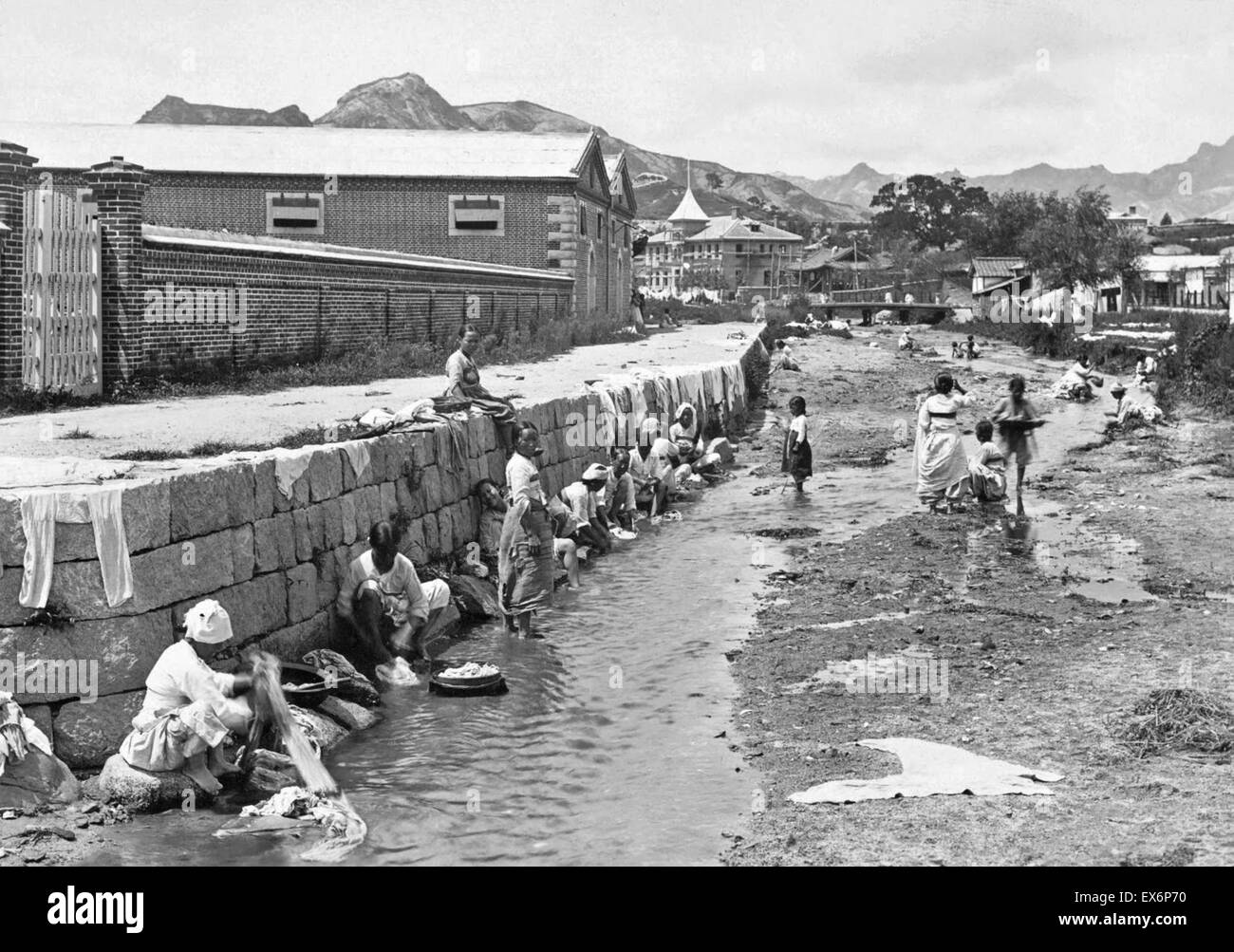 L'Inde sous le Raj britannique. Les femmes ont montré un lave-linge dans le ruisseau qui traverse une rue latérale, ca. 1904 Banque D'Images