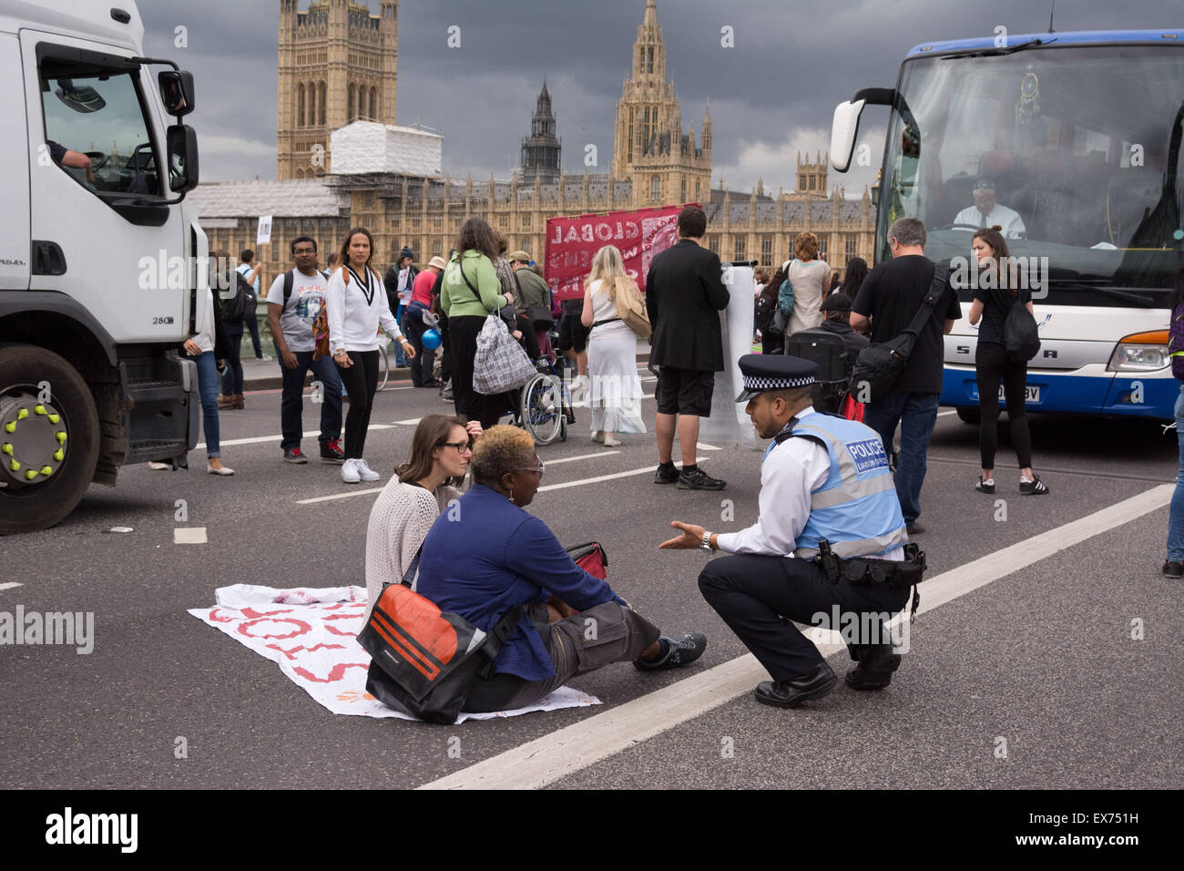 Londres, Royaume-Uni. 8 juillet, 2015. Un agent de soutien communautaire Police négocie avec des manifestants qui ont bloqué le pont de Westminster au cours d'une manifestation contre le budget. Anti-austérité et les militants d'invalidité publié balles multicolores en dehors de Whitehall, Downing Street, pour protester contre ce qu'ils considèrent comme un budget qui persécute et diabolise demandeurs de prestations, puis passés devant le Parlement et a bloqué le Westminster Bridge Crédit : Patricia Phillips/Alamy Live News Banque D'Images