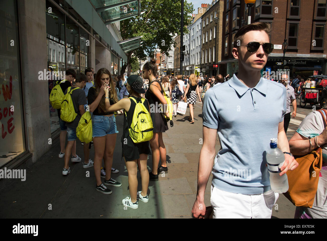 L'été à Londres, Angleterre, Royaume-Uni. Groupe d'étudiants touristes arrêter à Covent Garden pour allumer les cigarettes. Banque D'Images