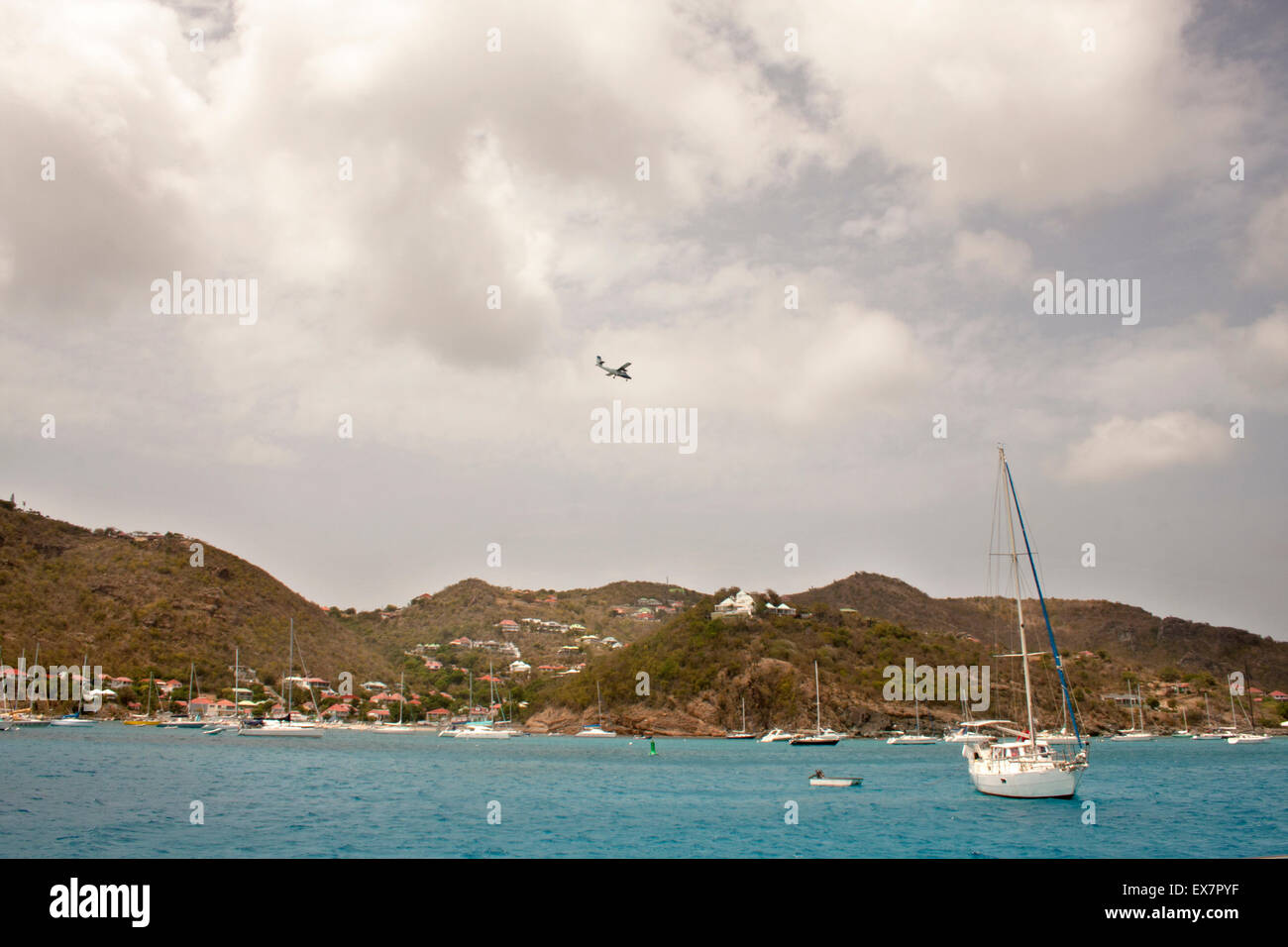 L'avion descend à travers les nuages, sur le port de Gustavia à terre sur l'île de Saint Barth Banque D'Images