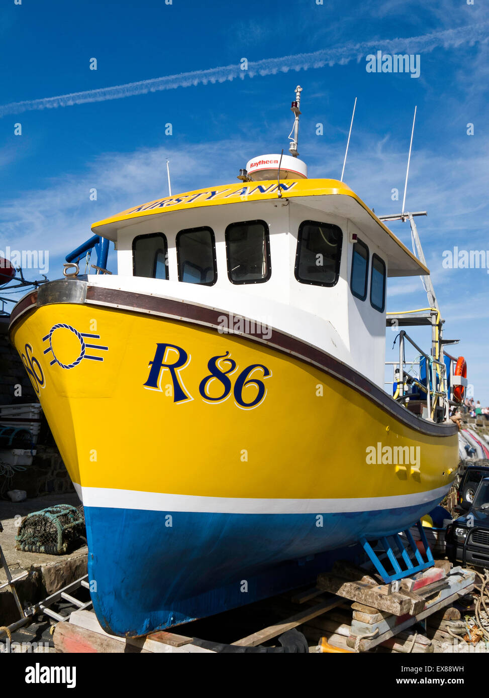 Repeint aux couleurs vives tiré au bateau de pêche sur des blocs dans le port de New Quay, Ceredigion, pays de Galles Banque D'Images