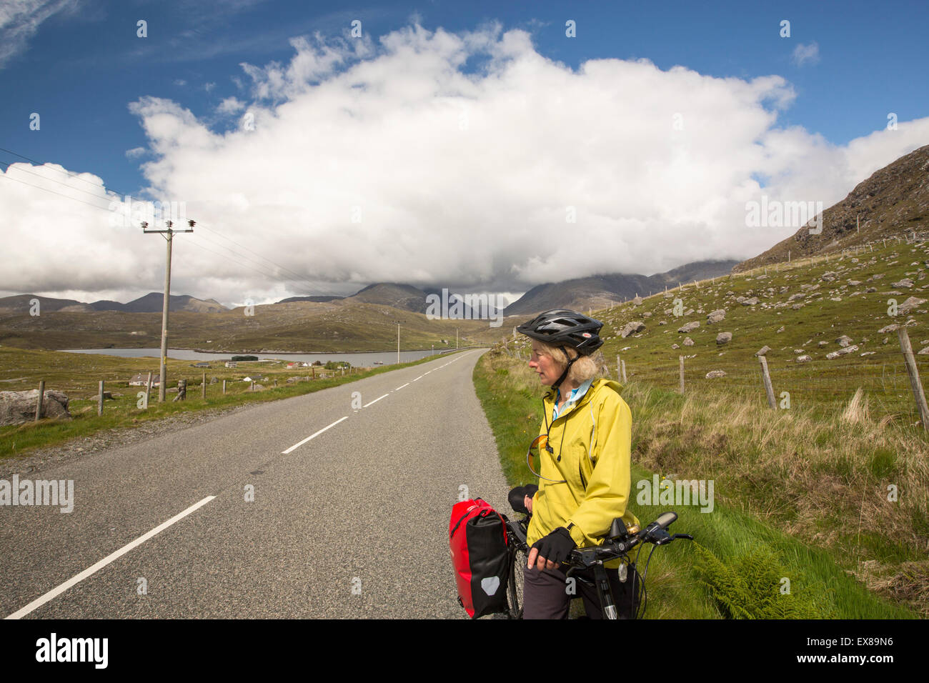 Une femme cyclotourisme à travers un paysage de montagnes au nord de Harris, Hébrides extérieures, en Écosse, au Royaume-Uni. Banque D'Images