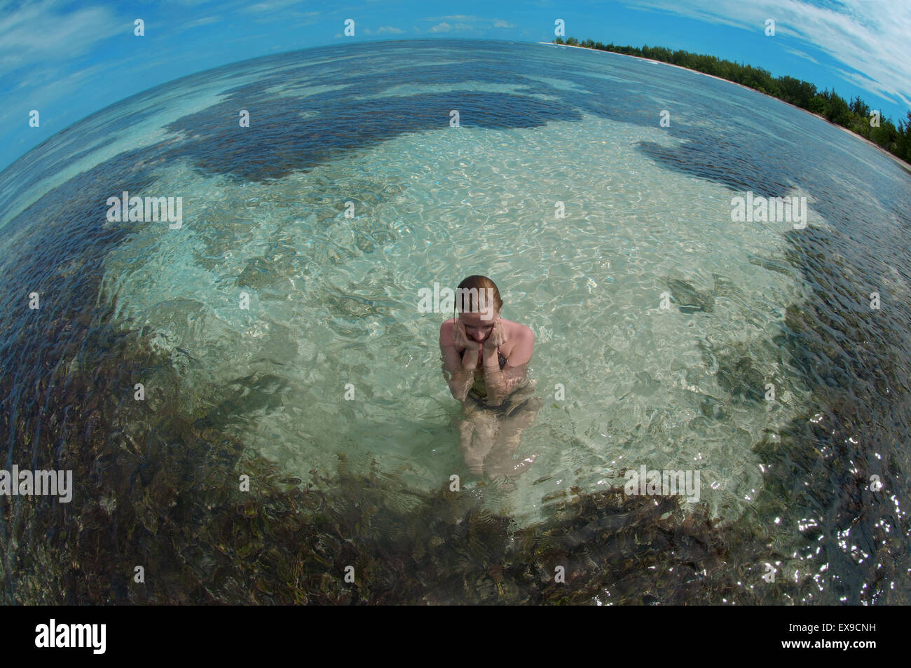 Une jeune femme est assise dans l'eau, Denis Island, de l'Océan Indien, les Seychelles Banque D'Images