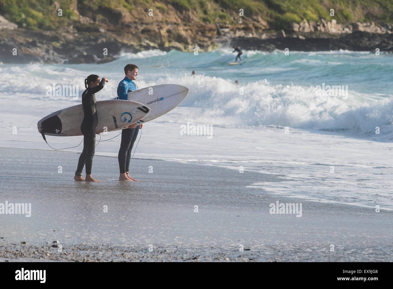 Surfers debout sur la plage de Fistral, Newquay en Cornouailles. Banque D'Images