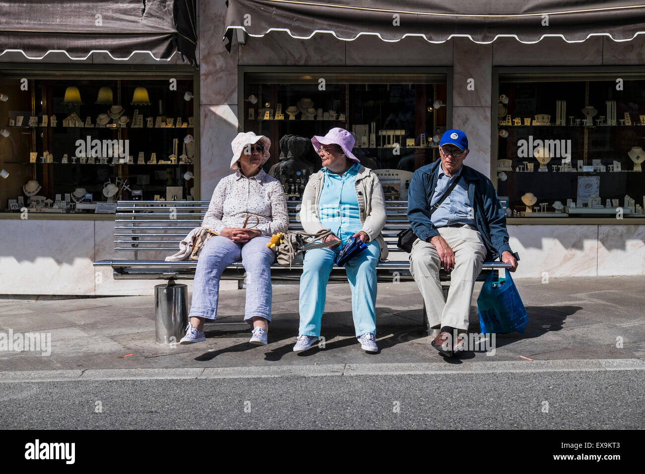 Trois des vacanciers se détendre sur un banc dans le centre-ville de Newquay en Cornouailles, Angleterre, Royaume-Uni. Banque D'Images