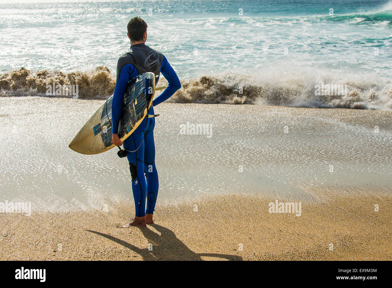 Un surfeur debout sur la plage de Fistral, Newquay en Cornouailles. UK. Banque D'Images