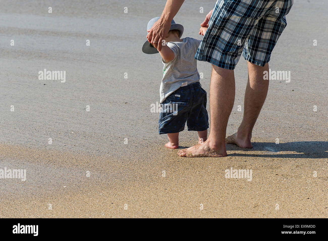 Un père en tenant son jeune fils à la plage pour la première fois. Banque D'Images