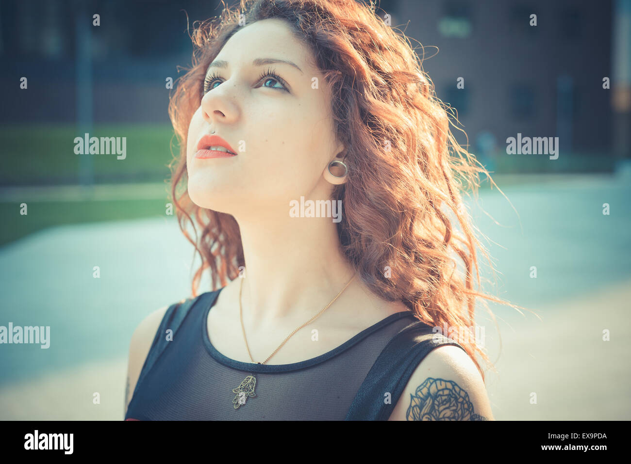 Belle jeune femme hippie avec les cheveux bouclés rouge dans la ville Banque D'Images