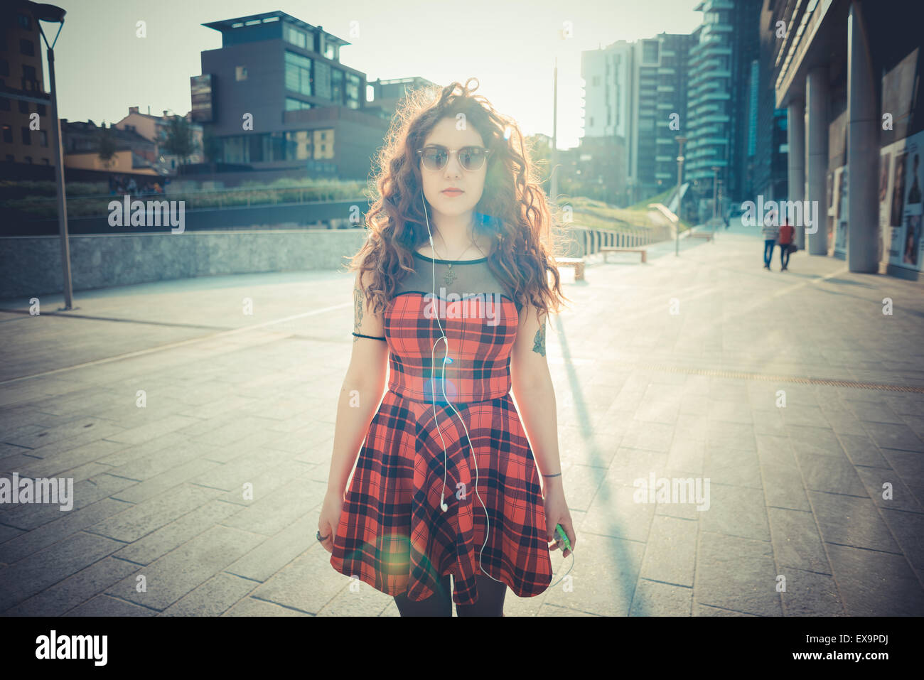 Belle jeune femme hippie avec les cheveux bouclés rouge dans la ville Banque D'Images