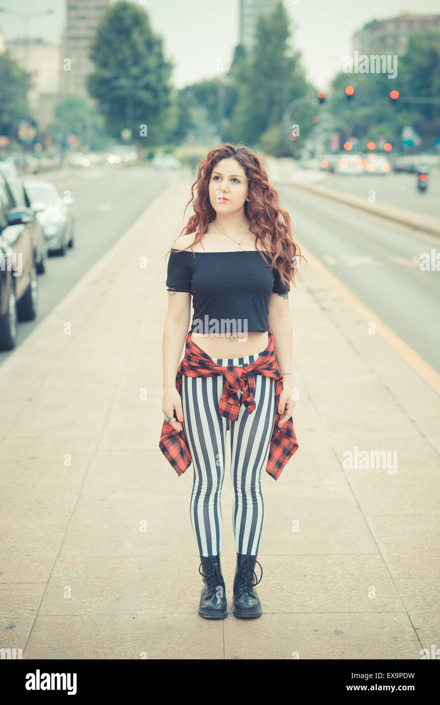 Belle jeune femme hippie avec les cheveux bouclés rouge dans la ville Banque D'Images