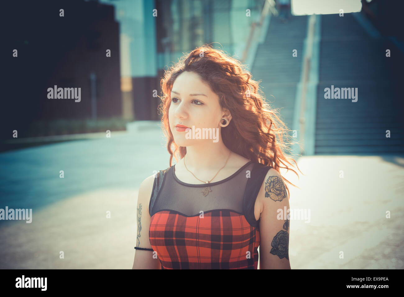 Belle jeune femme hippie avec les cheveux bouclés rouge dans la ville Banque D'Images