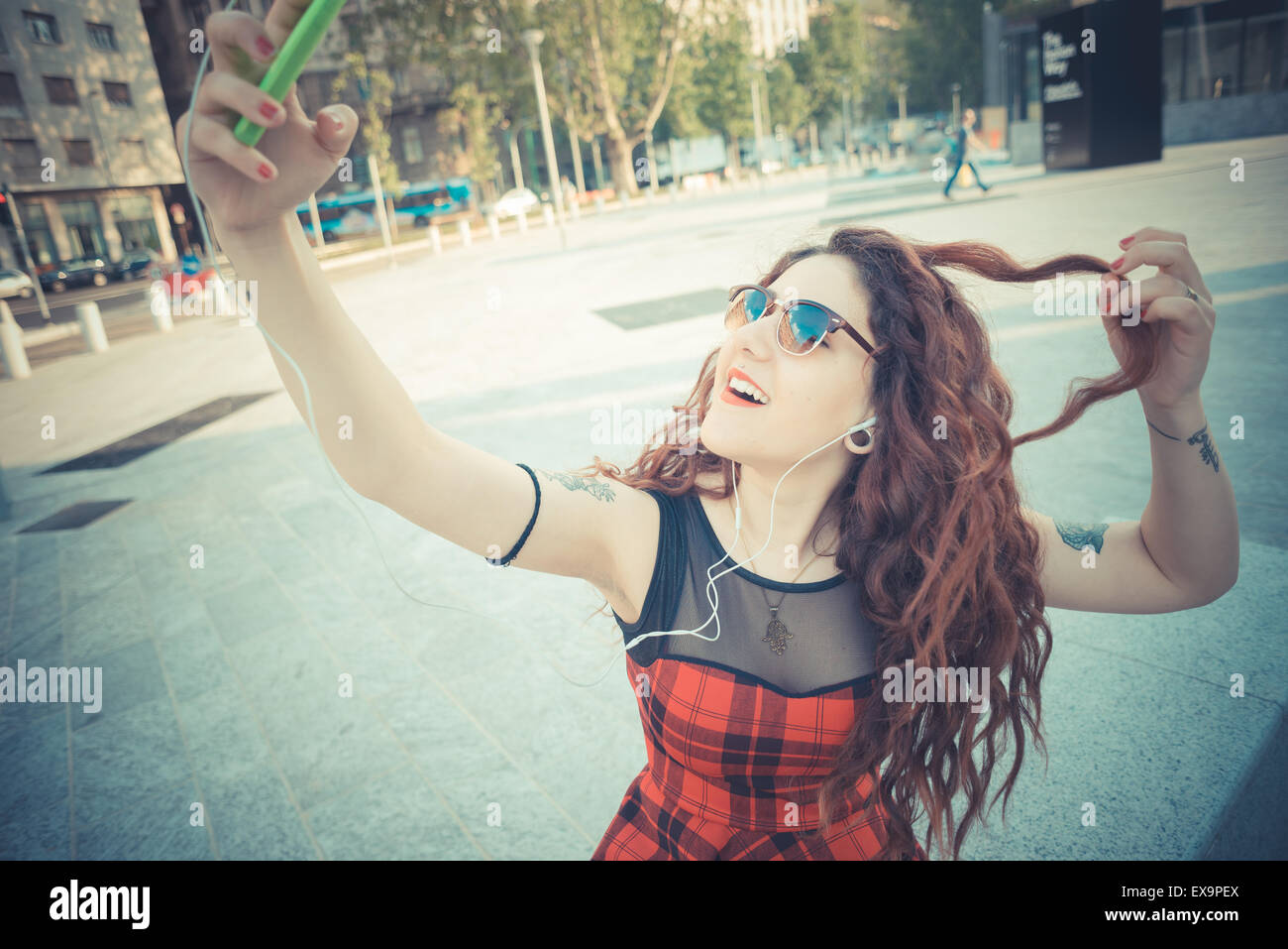 Belle jeune femme hippie avec les cheveux bouclés rouge dans la ville Banque D'Images
