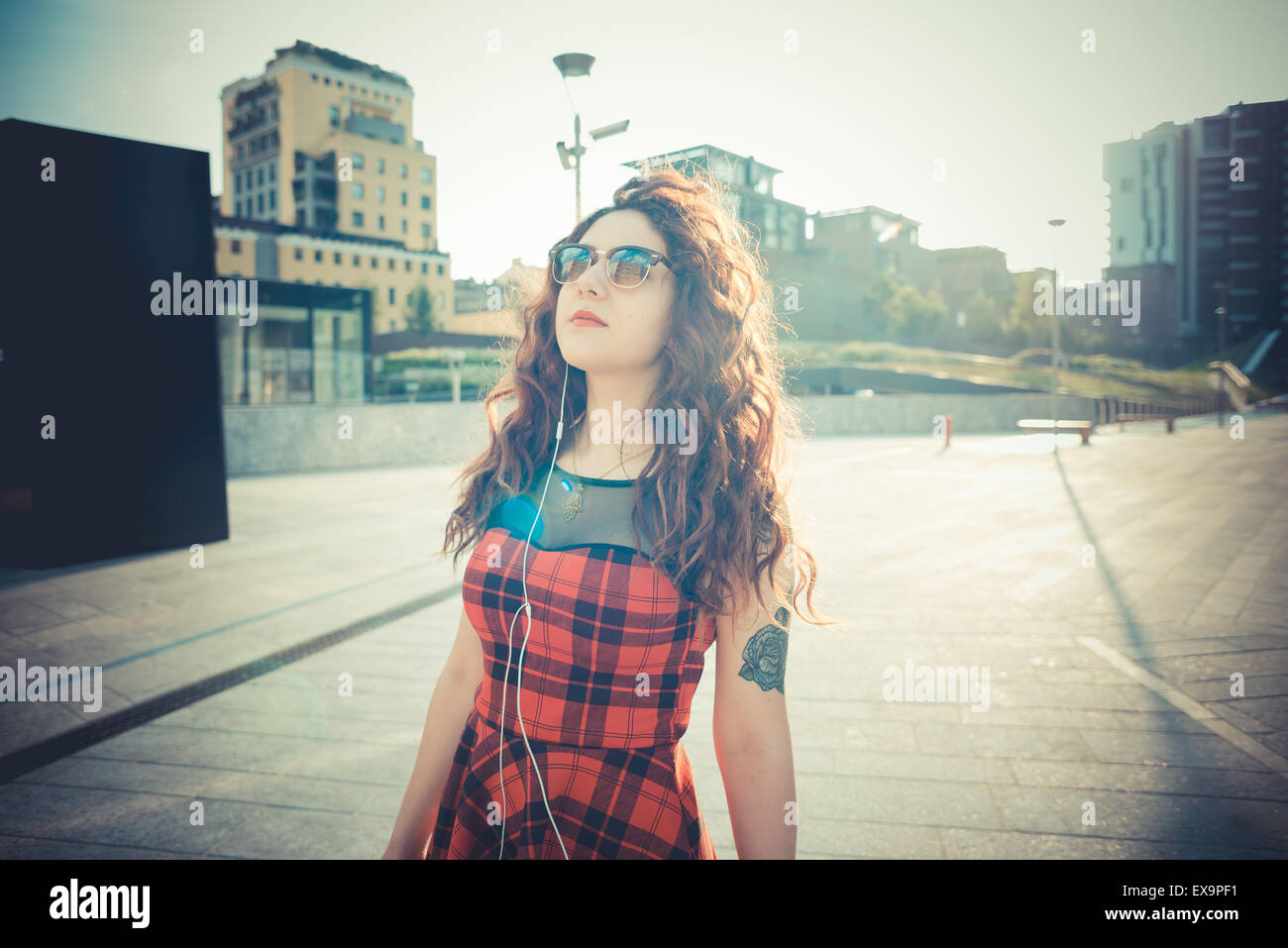 Belle jeune femme hippie avec les cheveux bouclés rouge dans la ville Banque D'Images