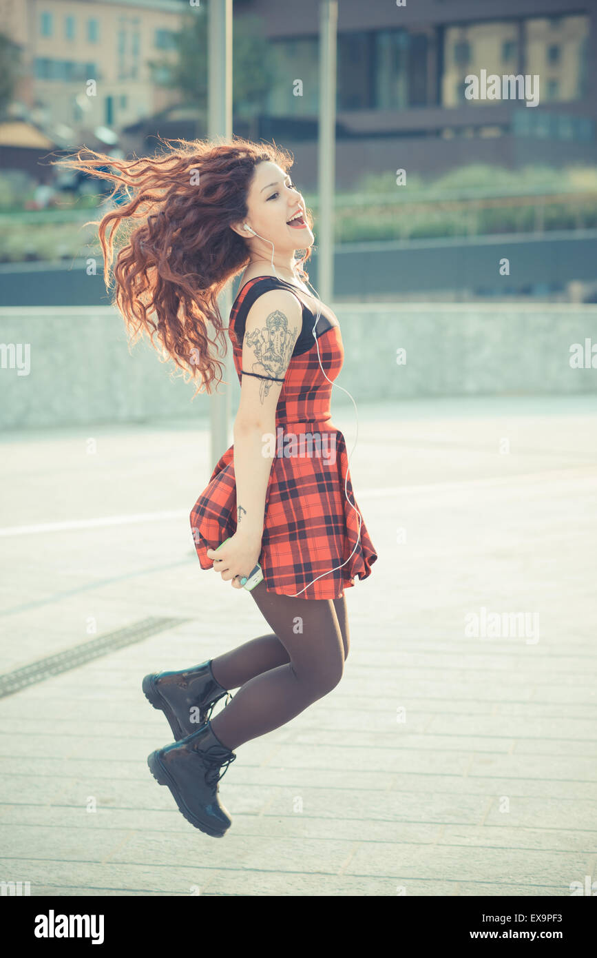 Belle jeune femme hippie avec les cheveux bouclés rouge dans la ville Banque D'Images